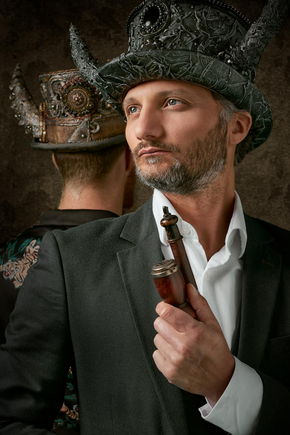 A man in a suit wearing a steampunk top hat with horns