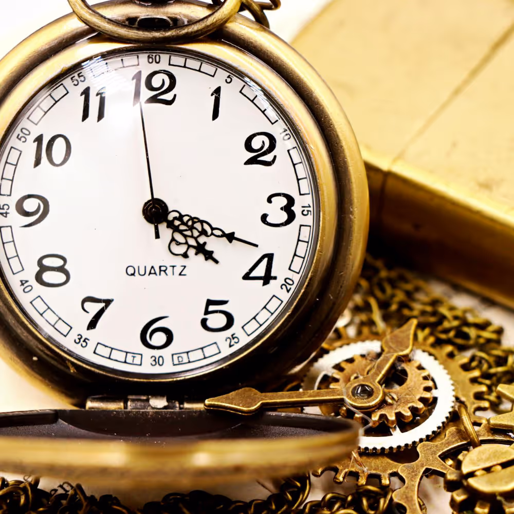 An antique pocket watch and brass cigarette lighter.