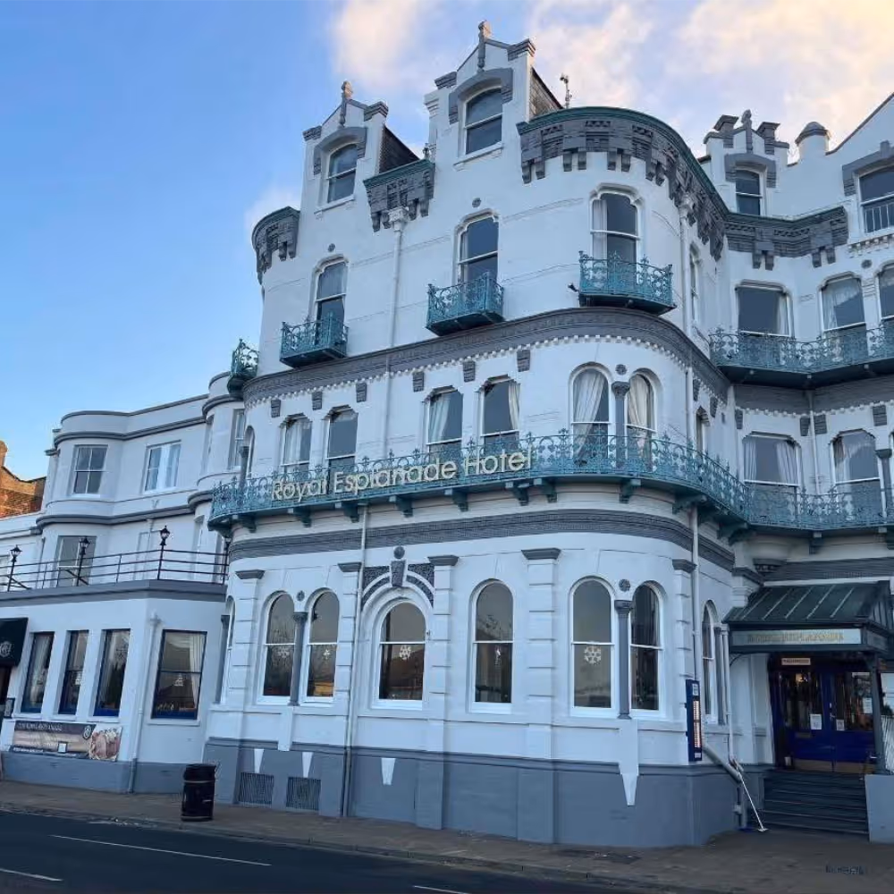 The exterior of an elegant white Victorian seafront hotel.