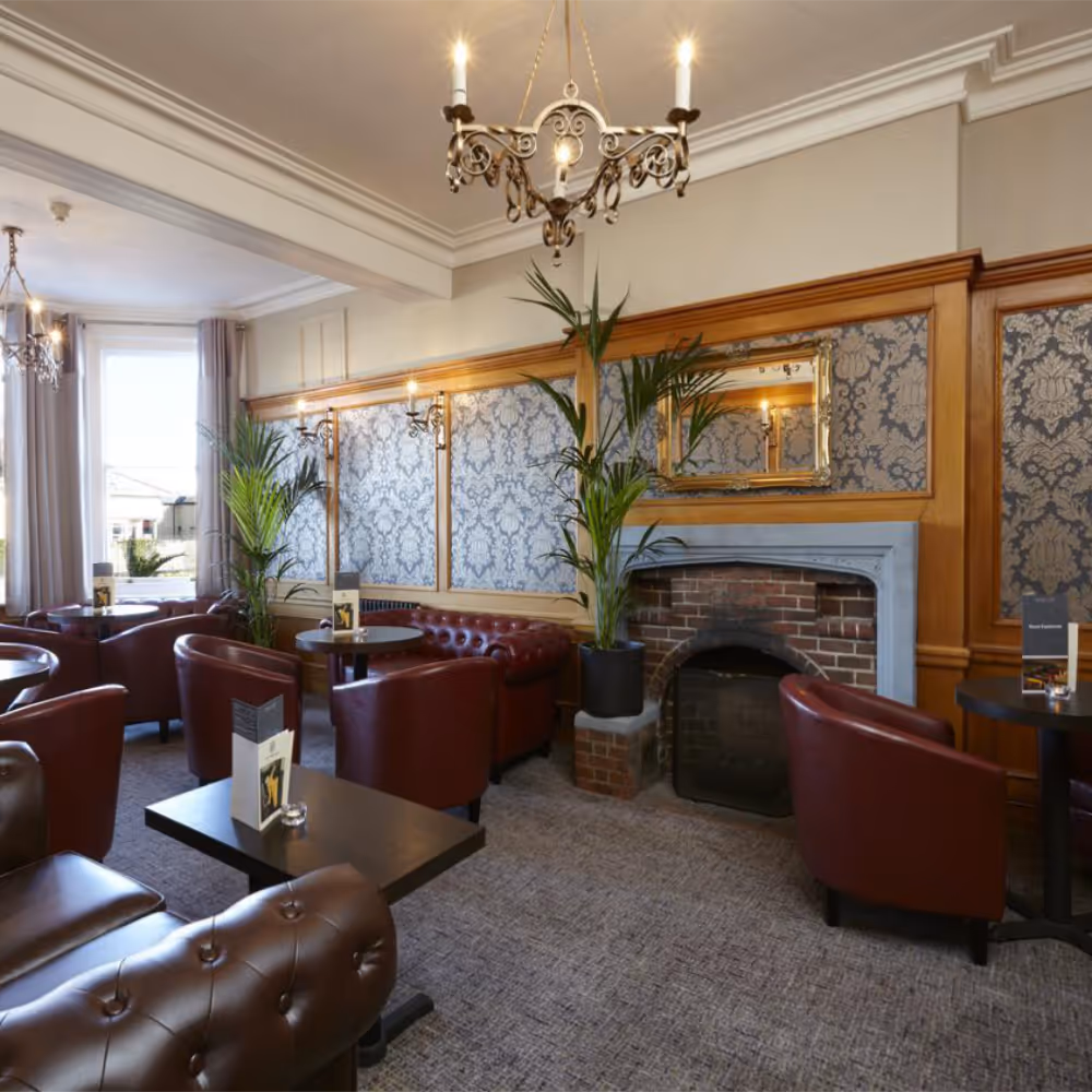 A an elegant hotel bar lounge with traditional decor and red leather armchairs.