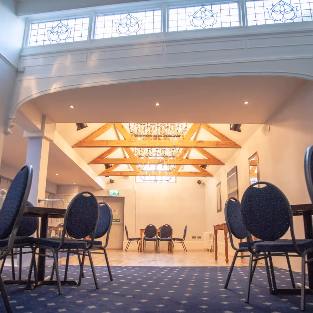 An elegant hotel function room with wooden ceiling beams.