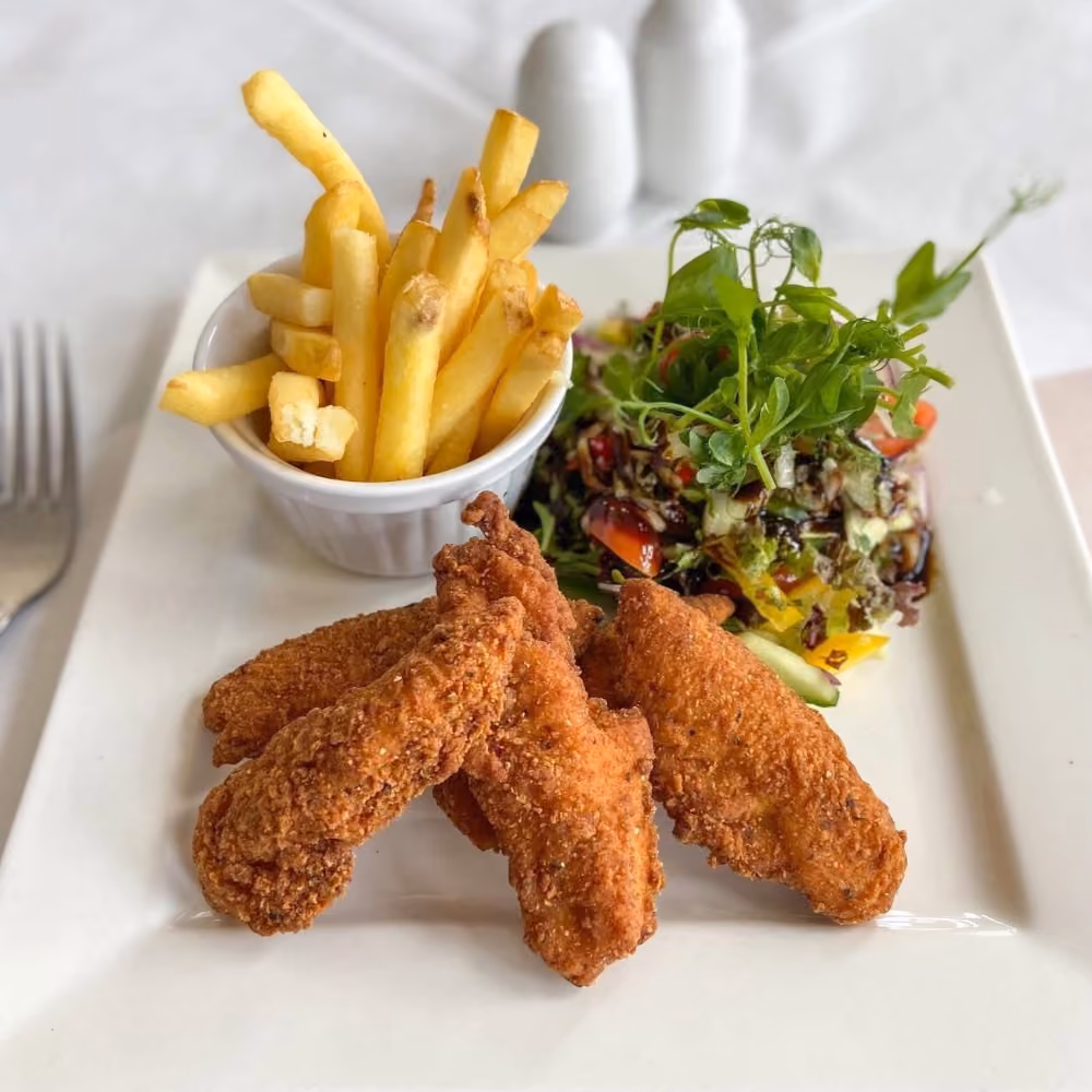 A plate of chicken goujons and fries in an elegant setting.