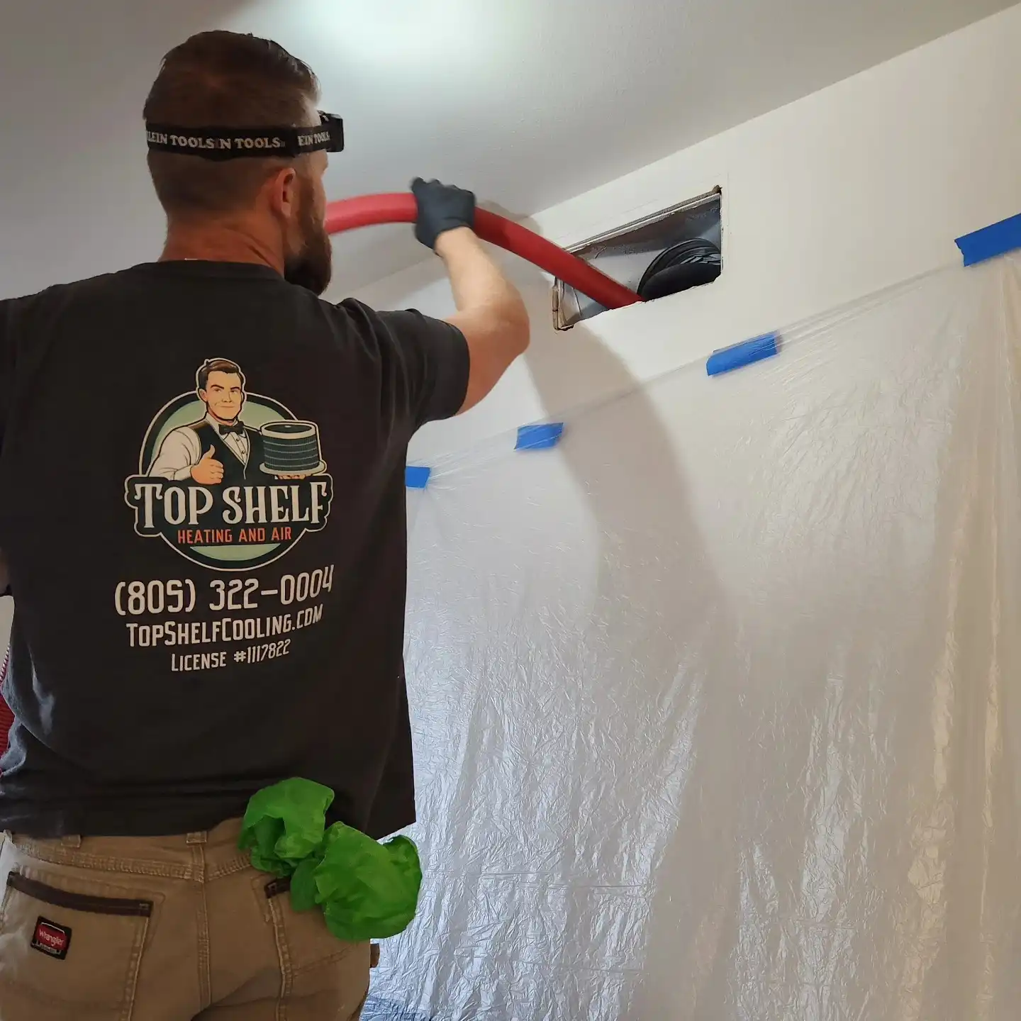 HVAC technician installing ductwork wearing Top Shelf Heating and Air shirt