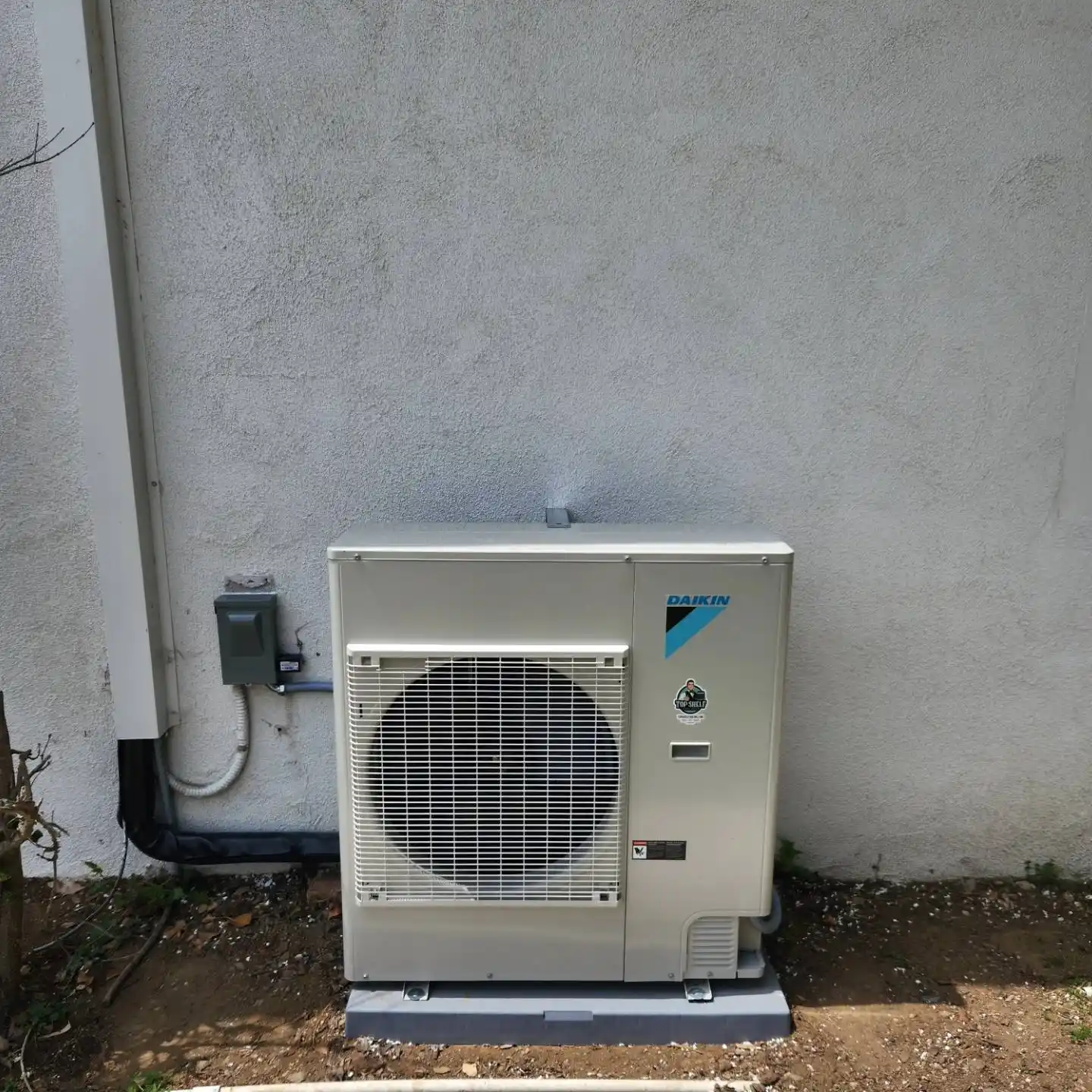 Newly installed outdoor air conditioning unit beside a brick house.