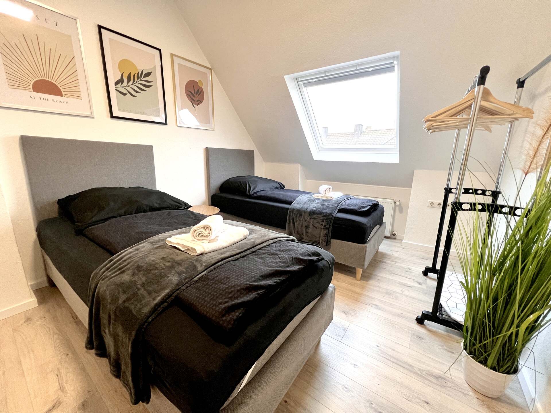 Zweibettzimmer mit schwarzer Bettwäsche und Pflanze
