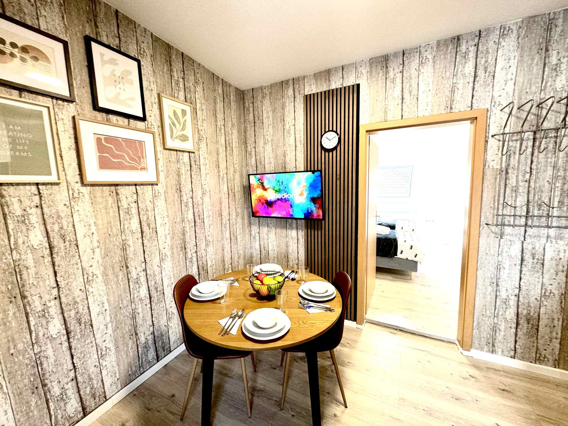 Gedeckter Tisch vor Fernseher und Wandbildern