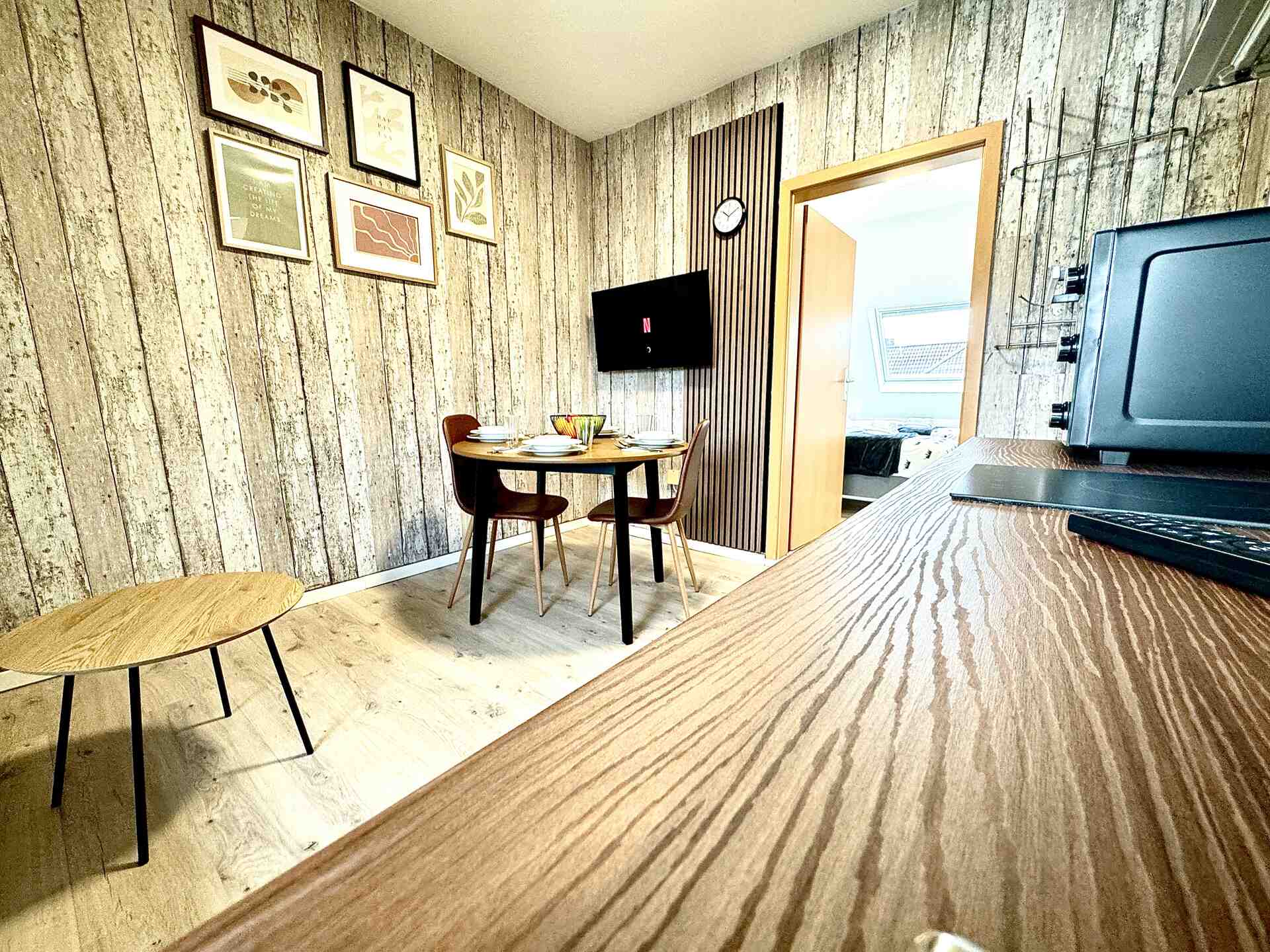 Gedeckter Tisch vor Fernseher und Wandbildern