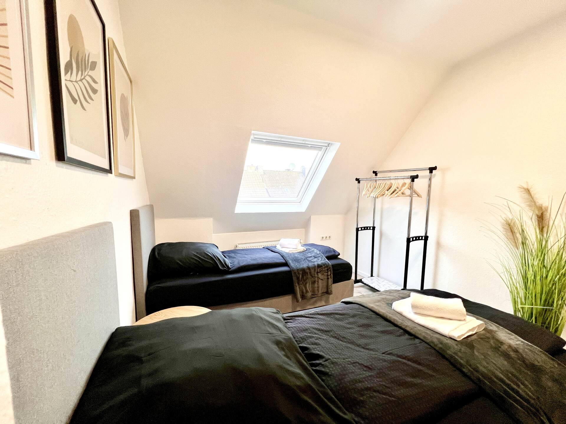 Dachzimmer mit zwei Betten und Kleiderständer