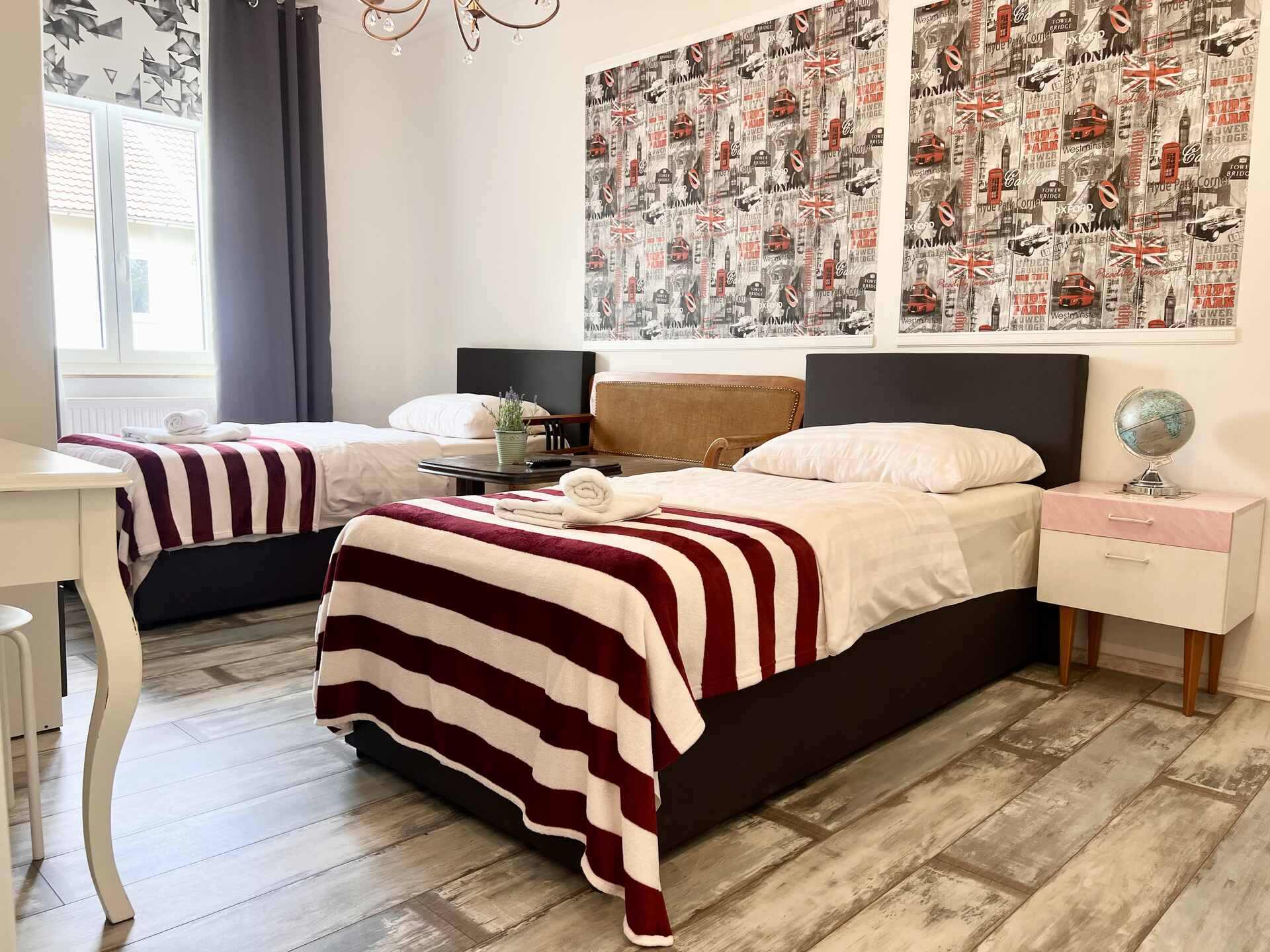 Helles Zweibettzimmer mit stilvoller London-Dekoration, gemütlicher Sitzecke und modernem Holzboden.
