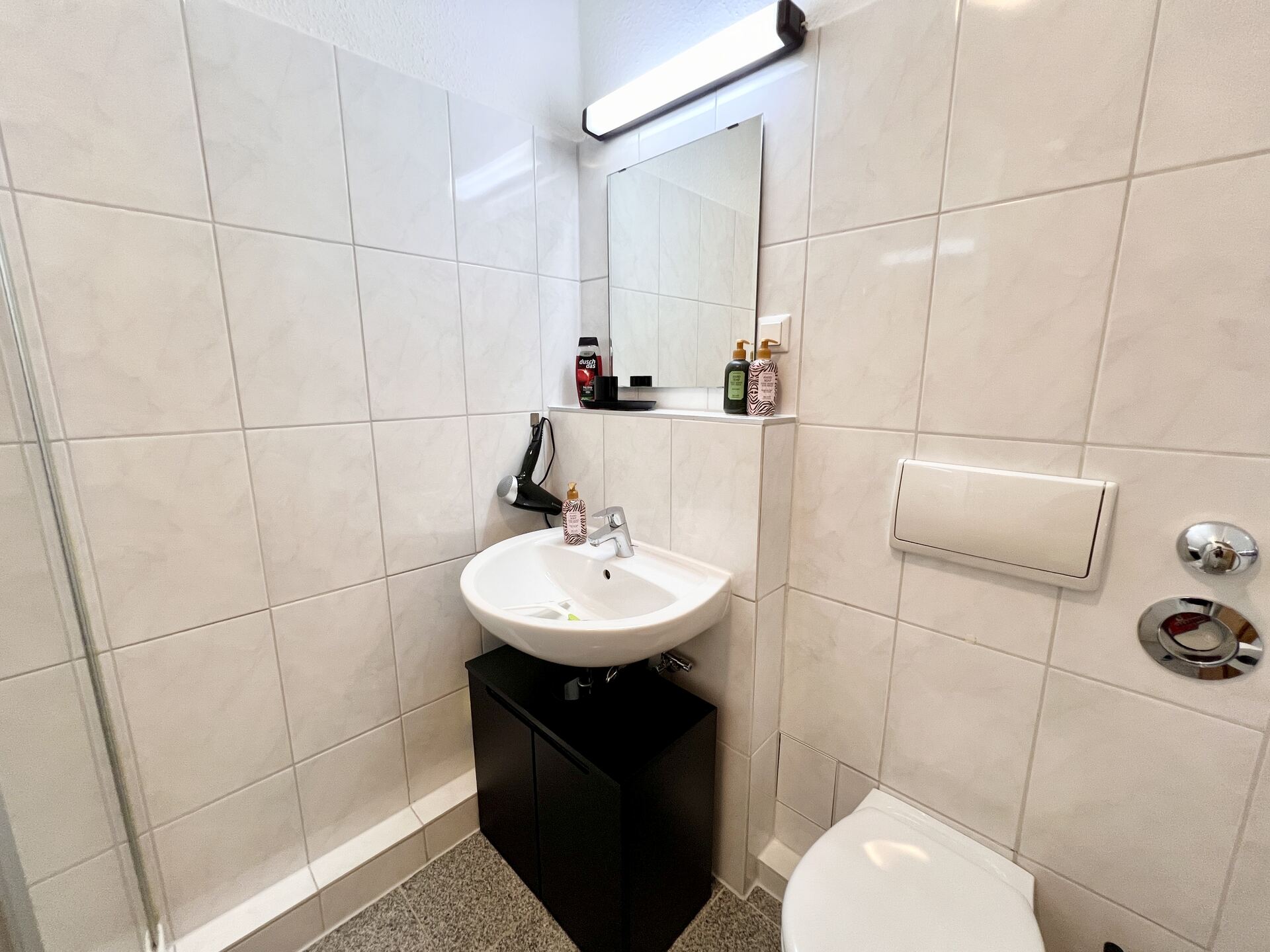 Waschbecken mit Spiegel und schwarzen Unterschrank