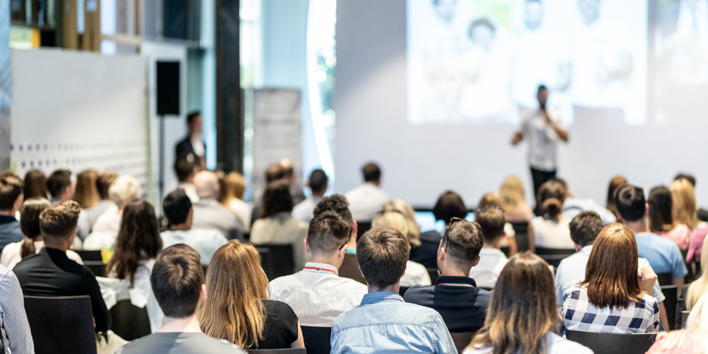 Security and risk management professionals attending industry summit presentation, audience engaged in conference session
