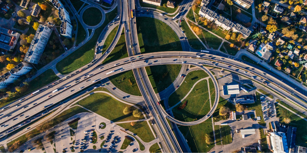 Complex highway interchange leading toward a dense city skyline, representing the integration of alternative data signals with traditional risk management.