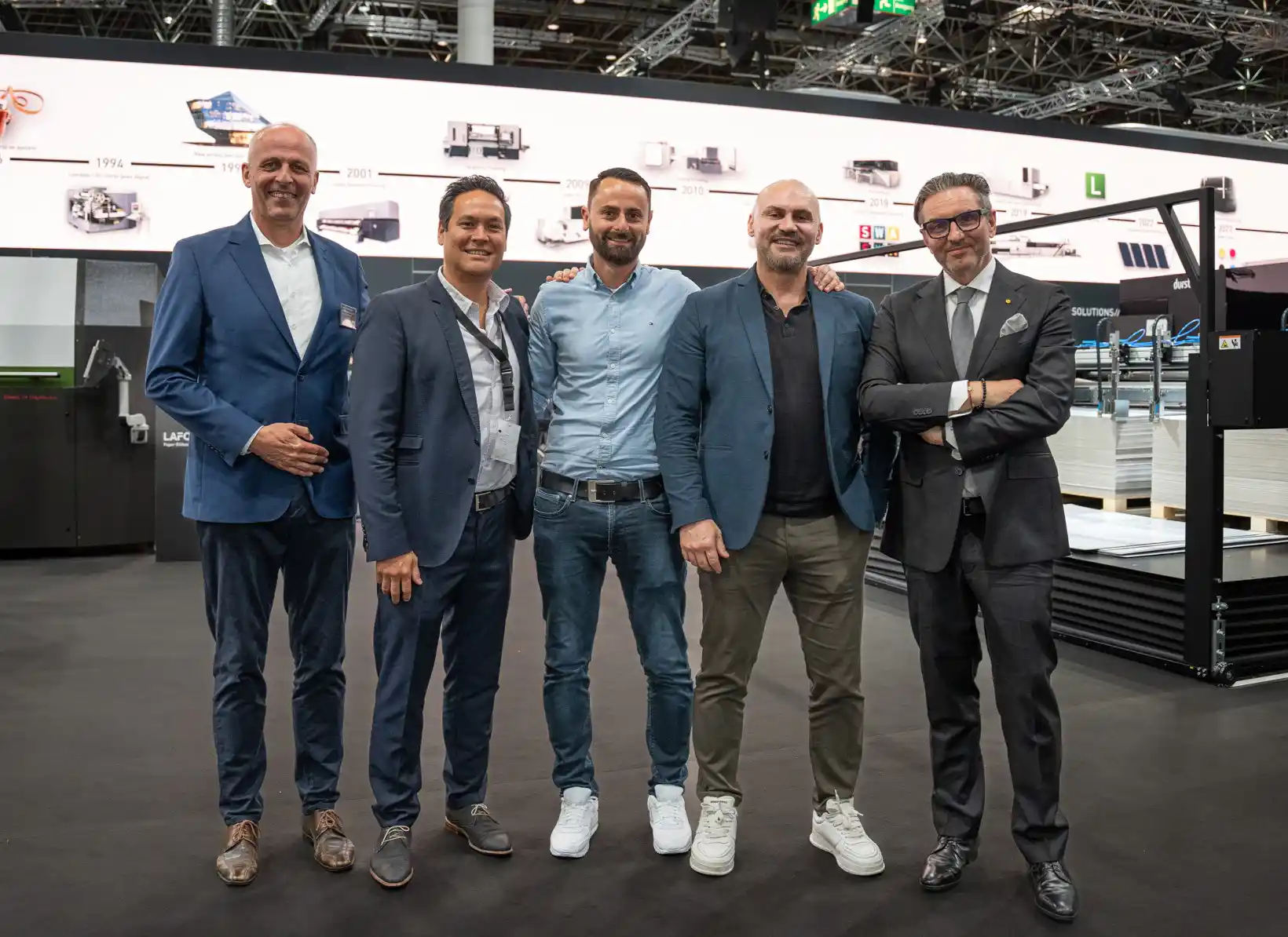 5 männer im anzug auf einer messe