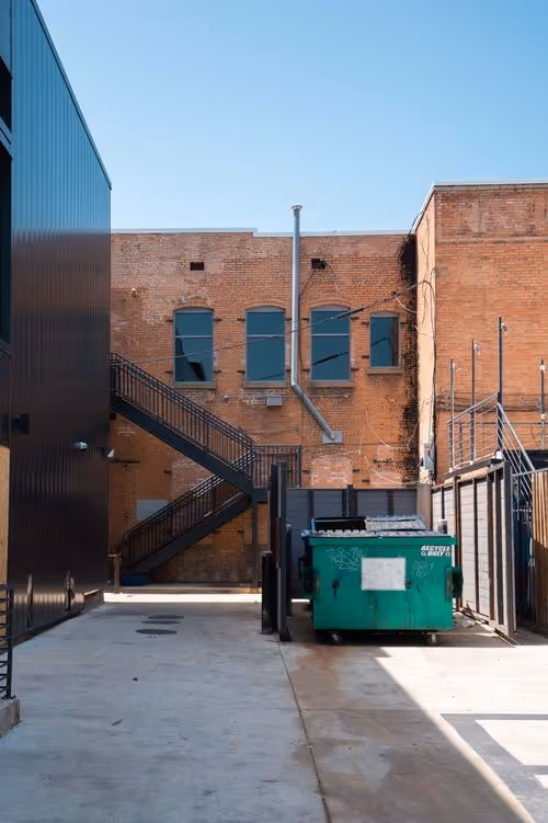 green dsq trashcan placed in front of a building