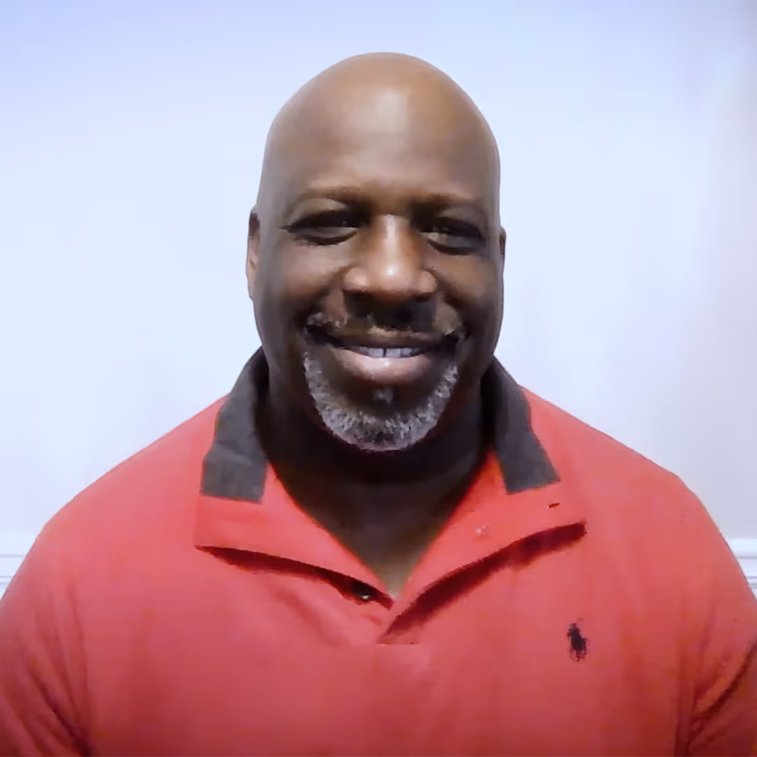 a smiling black man that is putting on a red shirt