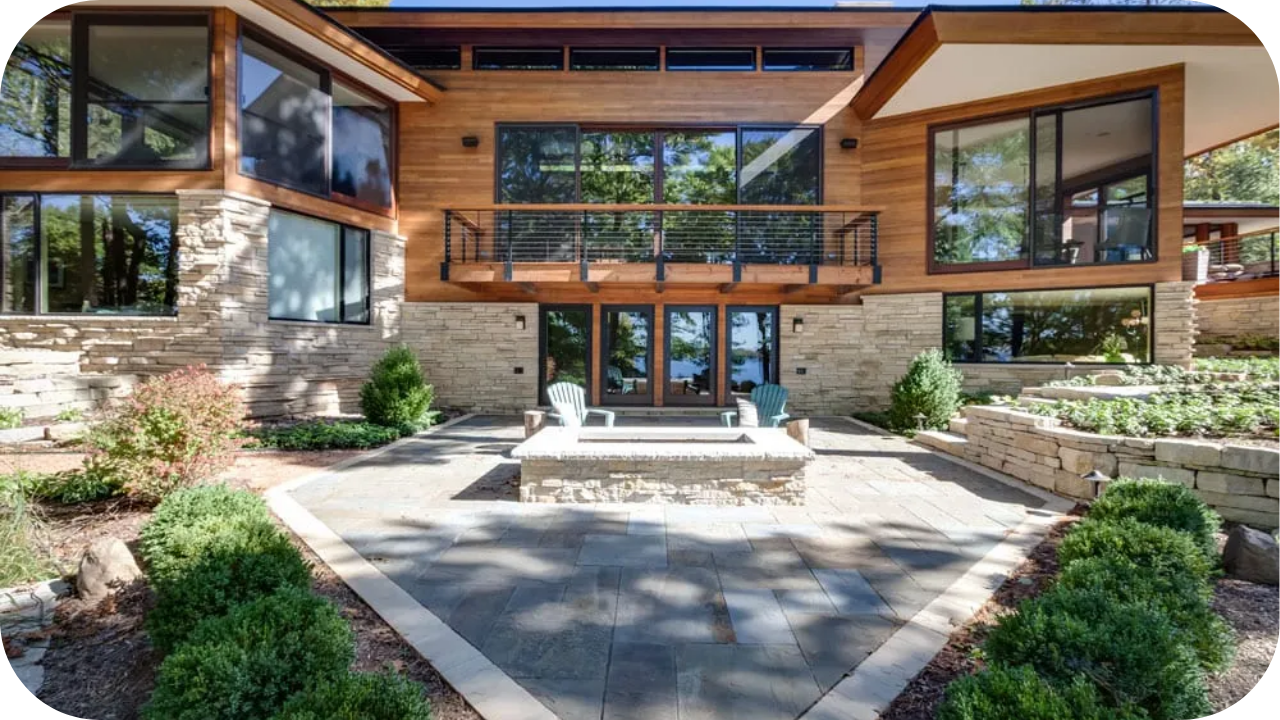 Mid-century modern home with stone and timber exterior, expansive glass windows, and open design blending indoor-outdoor living.