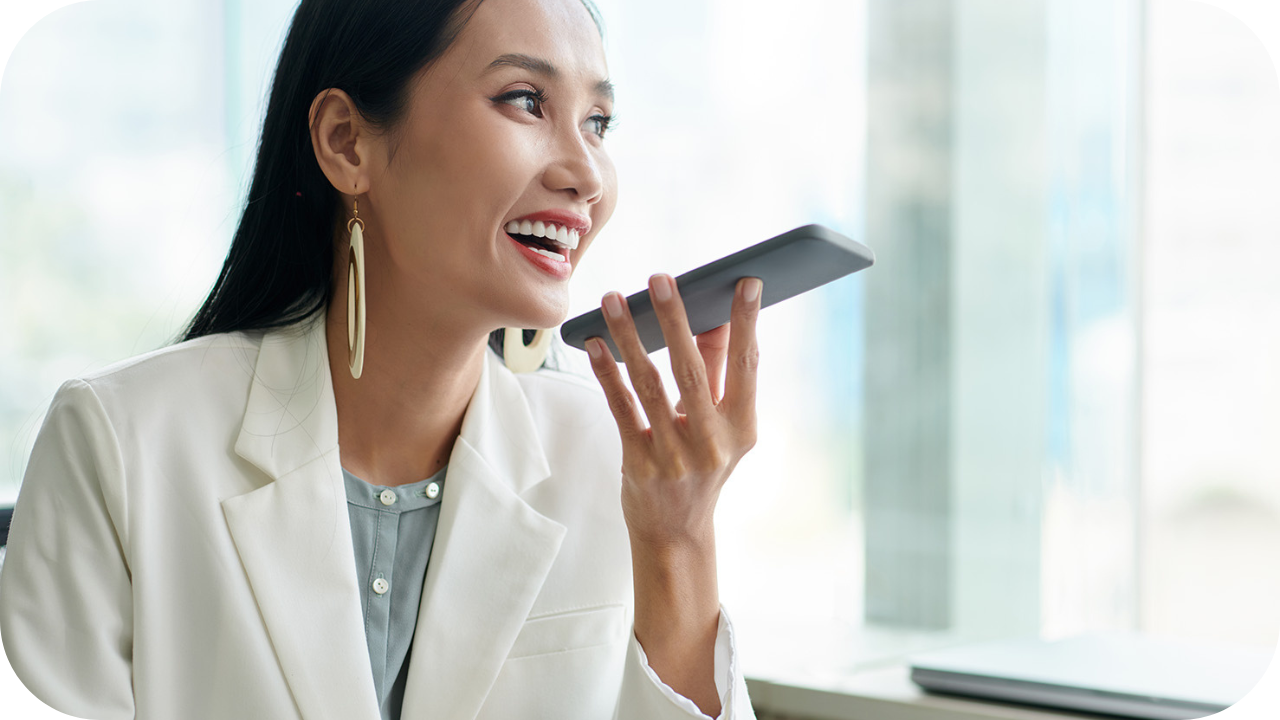 Smiling woman using a smart home voice assistant device in living room, showing hands-free control of daily household tasks.