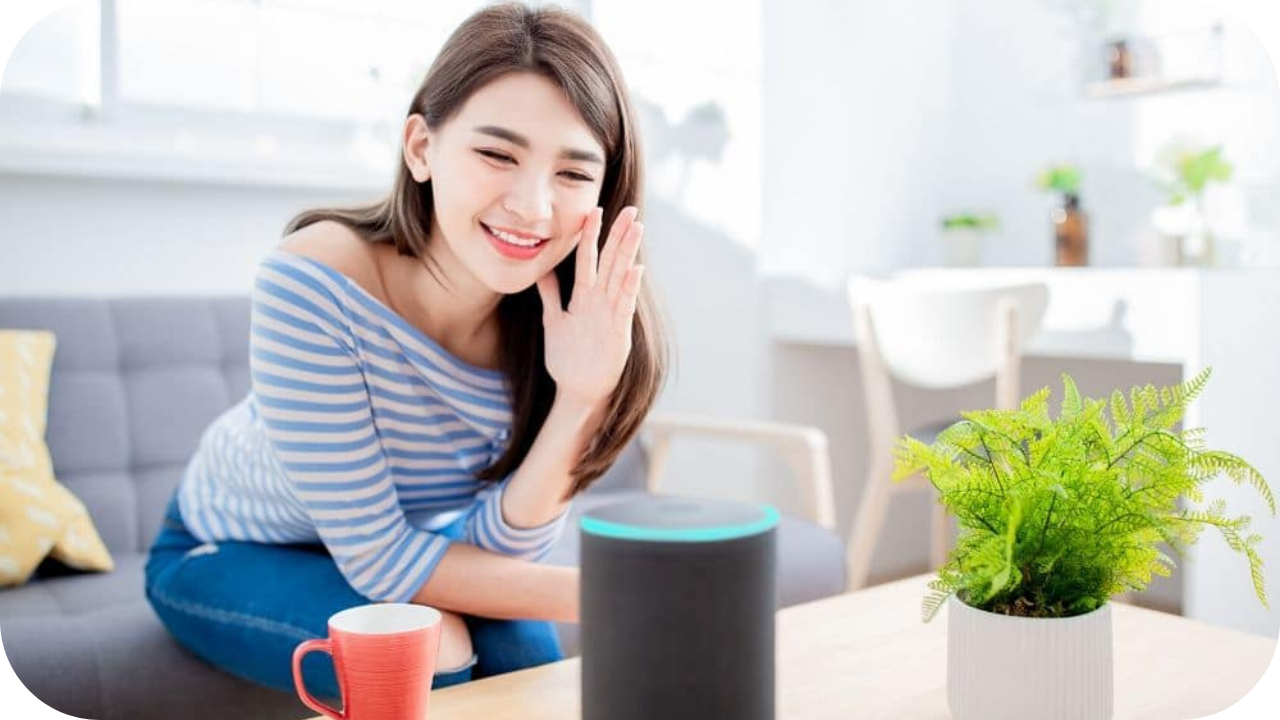 Smiling woman using a smart home voice assistant device in the living room, showing hands-free control of daily household tasks.