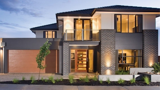 Modern two-storey home with brick and render exterior, glass balcony, large windows, timber garage door, and front lights.