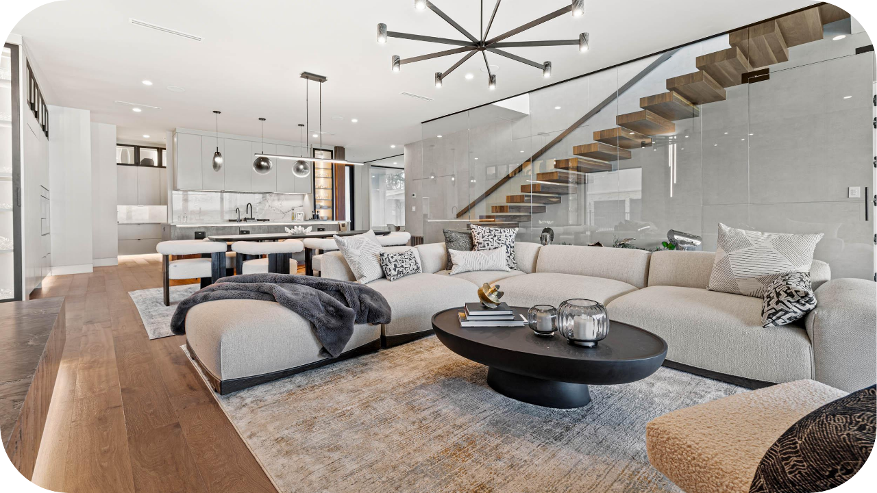 Stylish modern living room with neutral sectional sofa, open-plan kitchen, wooden floors, and floating staircase.