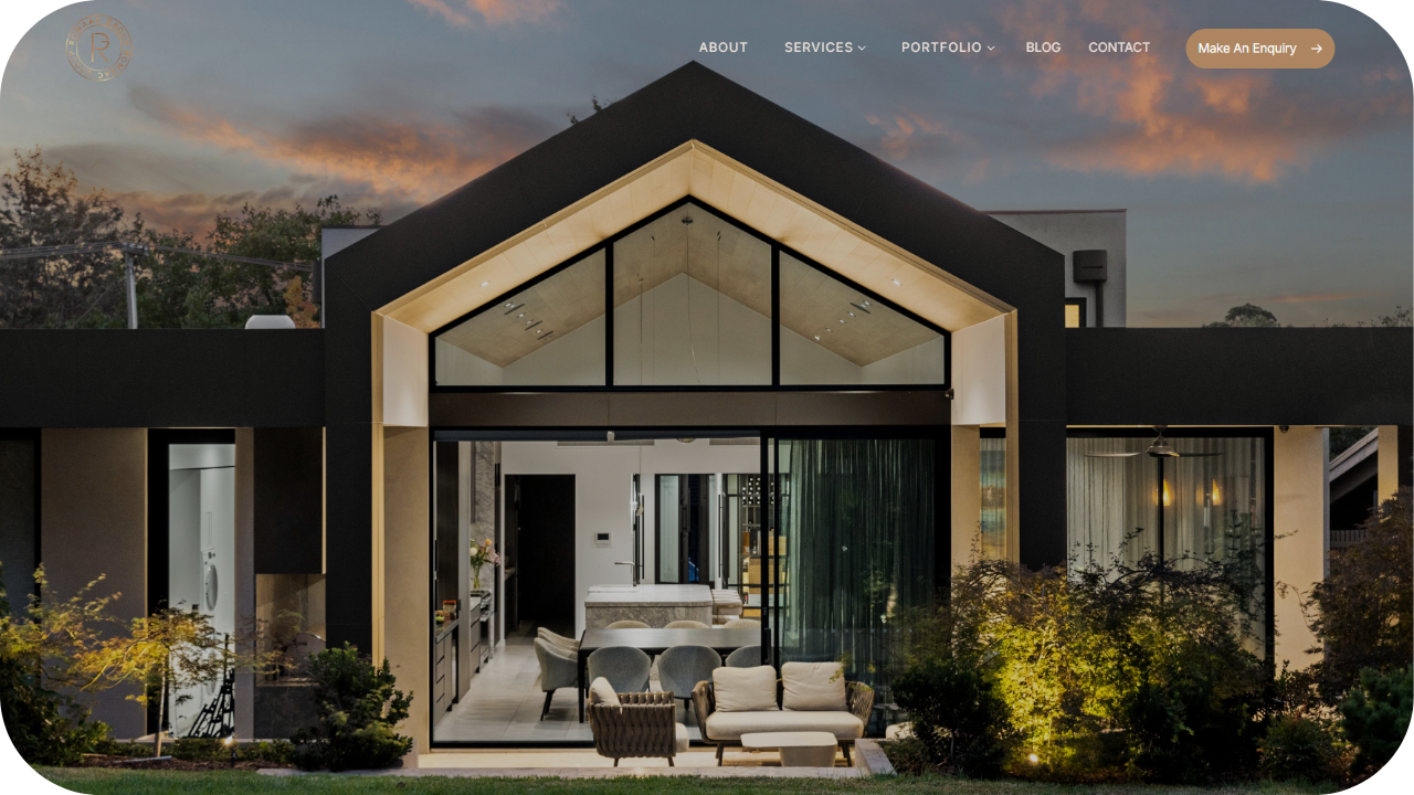 Contemporary home exterior with large glass windows, outdoor seating, and warm evening lighting.