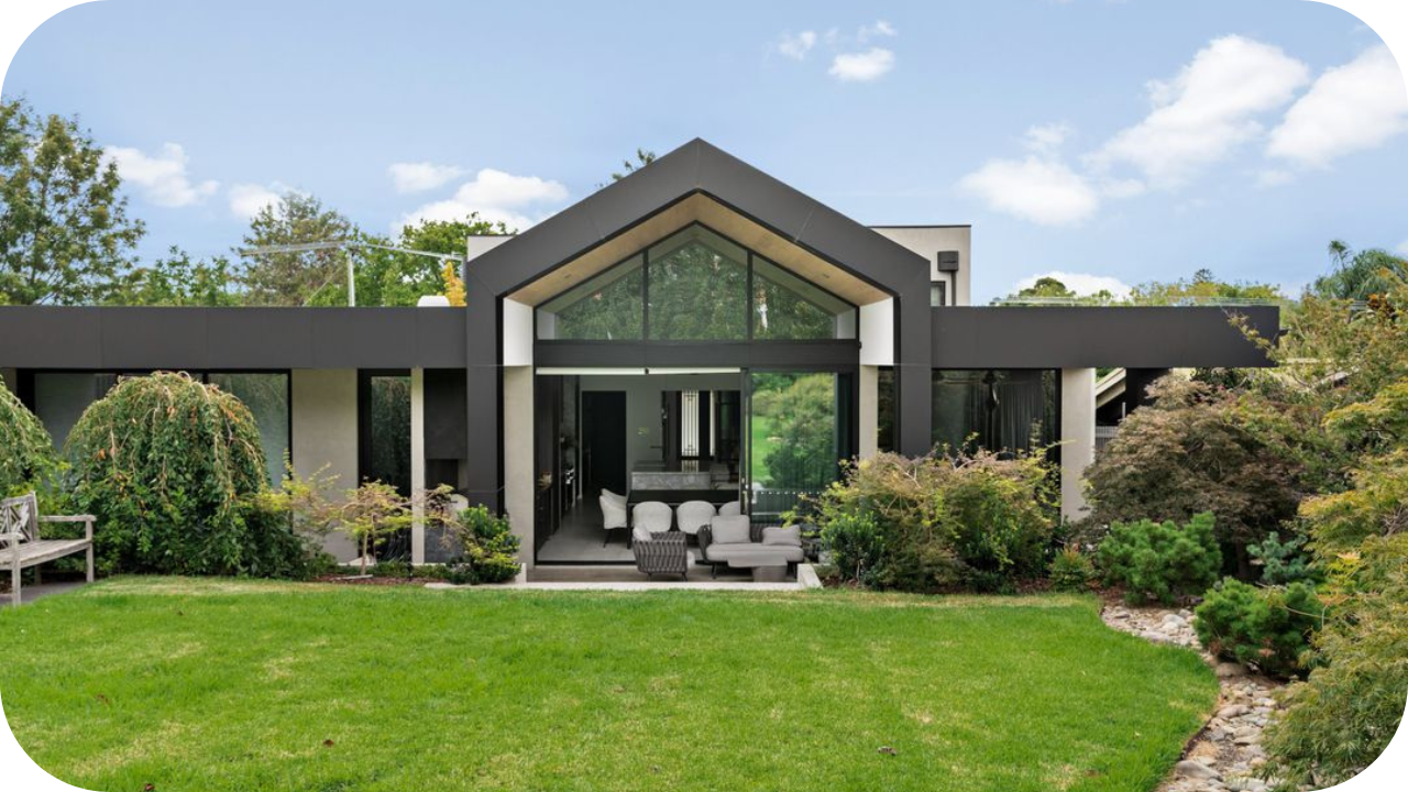 Contemporary Melbourne home with a gable roof, black-framed windows, and open indoor-outdoor living space surrounded by greenery.
