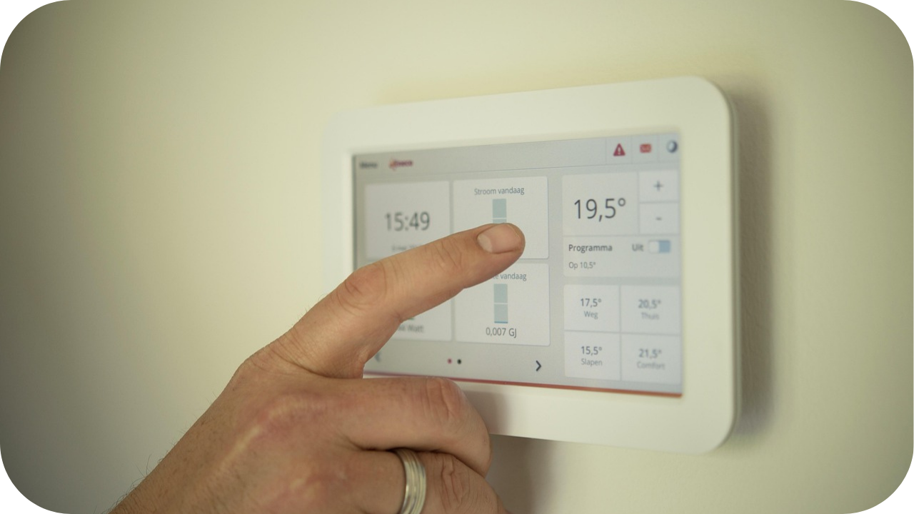 Hand adjusting a smart home thermostat on a digital control panel to manage indoor temperature settings.