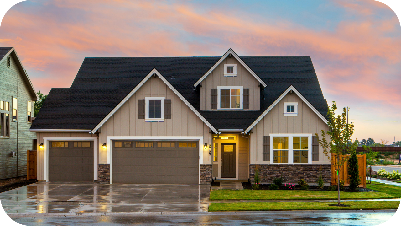 Contemporary suburban home with beige cladding, black roof, and double garage under a colourful sunset sky.