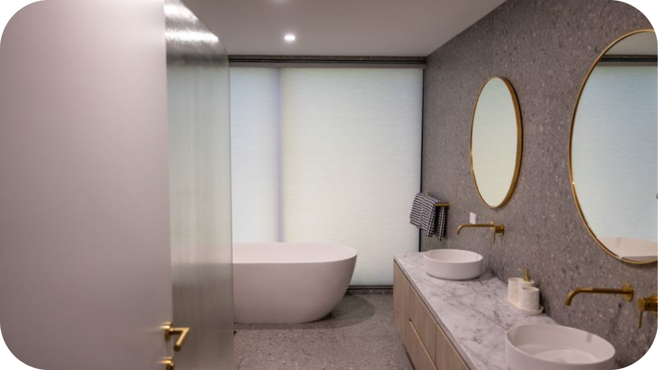 A contemporary bathroom with a freestanding tub, double marble vanity, gold accents, and soft filtered light, reflecting luxury interior style in Brisbane and Melbourne homes.