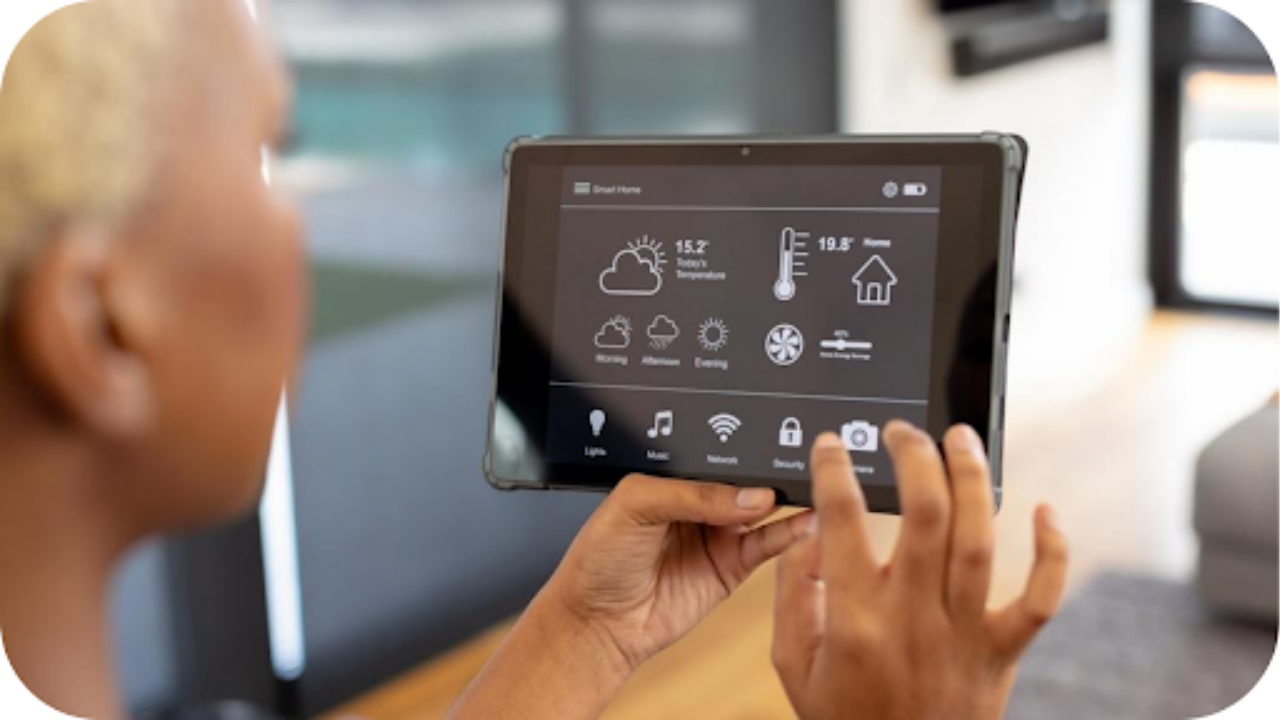 Person adjusting home settings on a smart tablet interface showing climate, lighting, security, and energy controls in a modern connected home