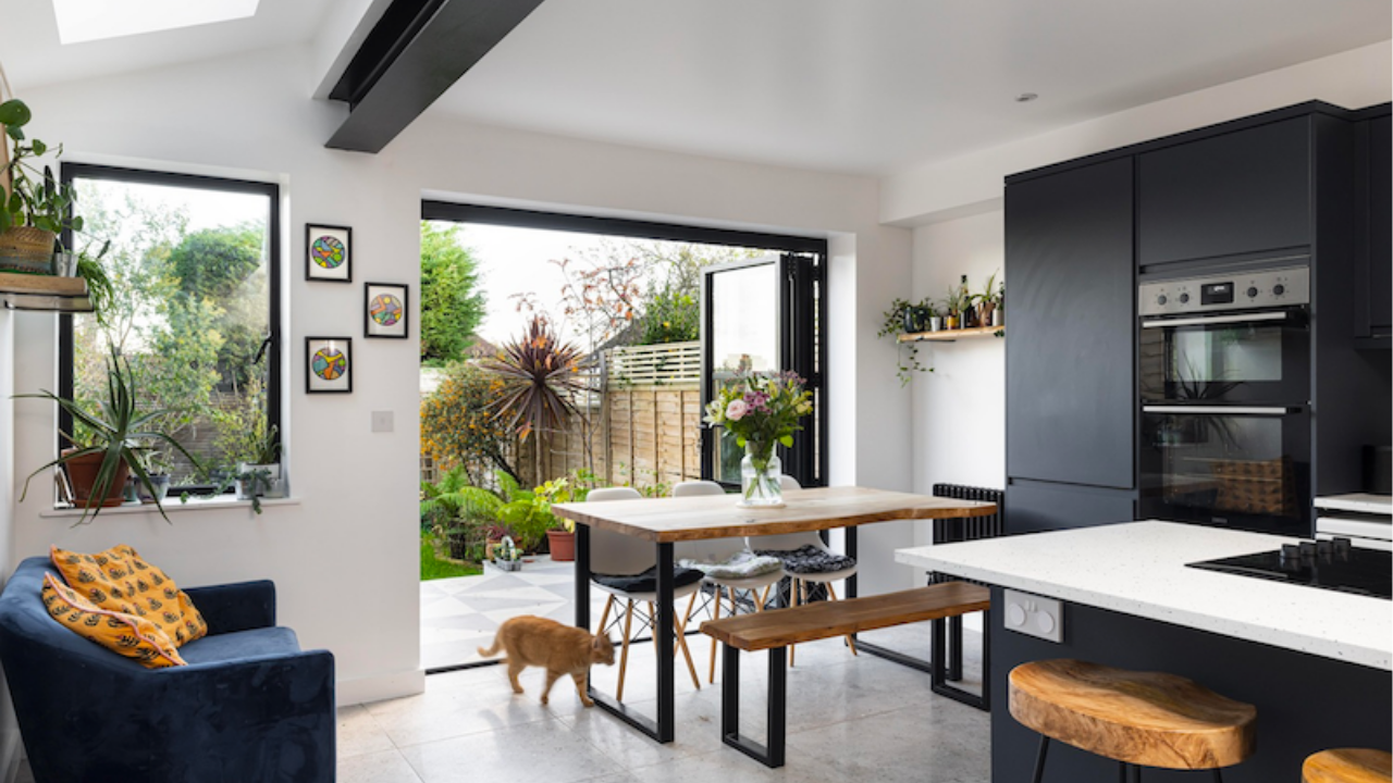 Open plan kitchen and dining area with large glass doors opening to a bright garden, featuring natural light and modern family-friendly design.