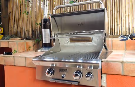 Stainless steel built-in grill with open lid on outdoor kitchen counter