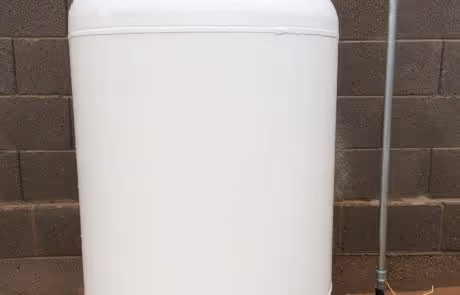 Large white storage tank or container against brick wall with metal pipe