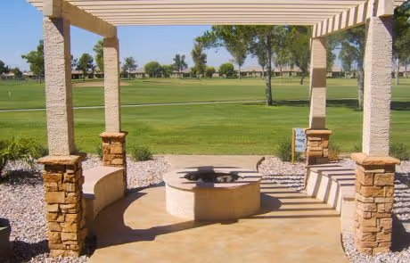 Stone pergola overlooking a green golf course with landscaped surroundings