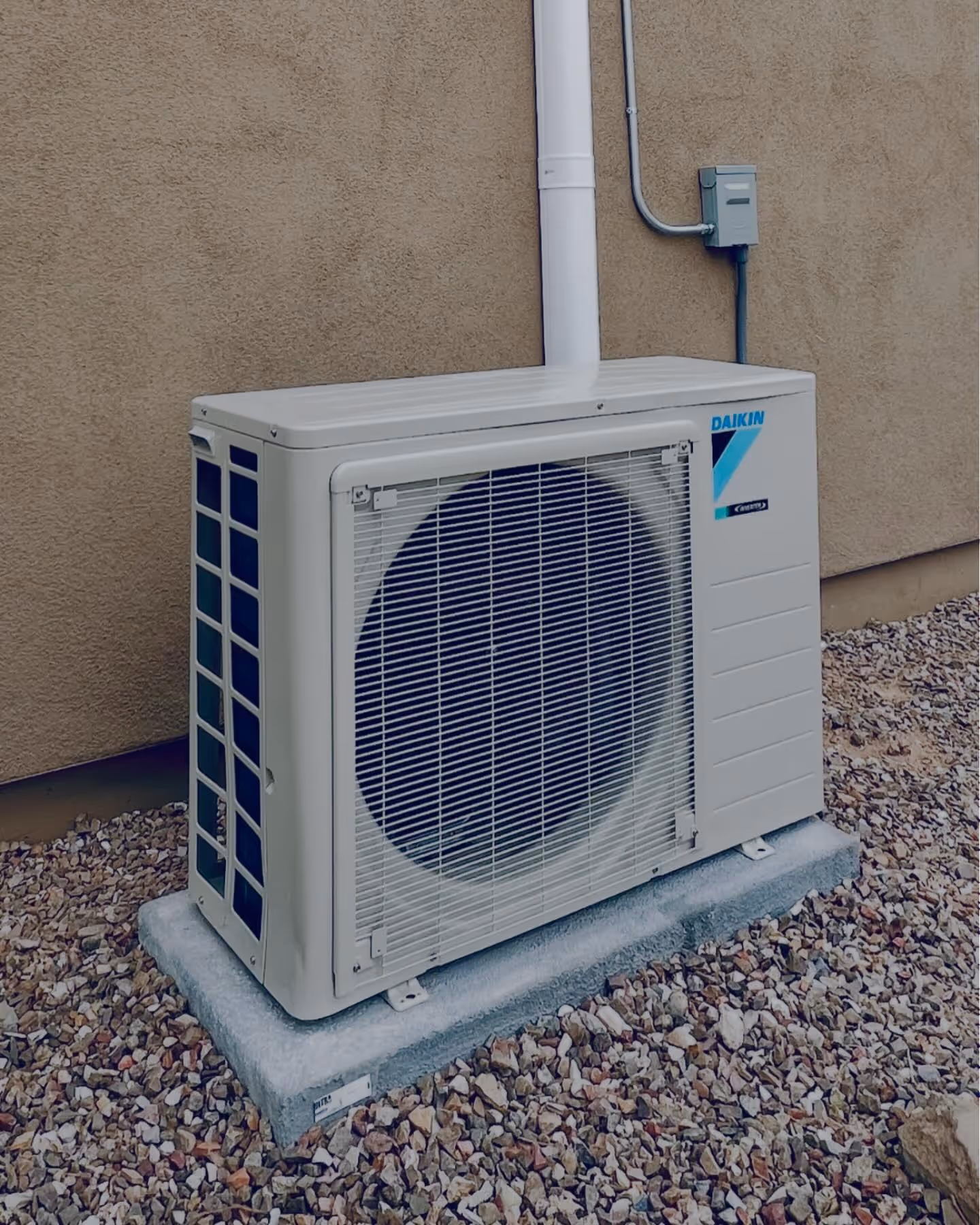 Daikin air conditioning unit mounted on concrete pad near building wall