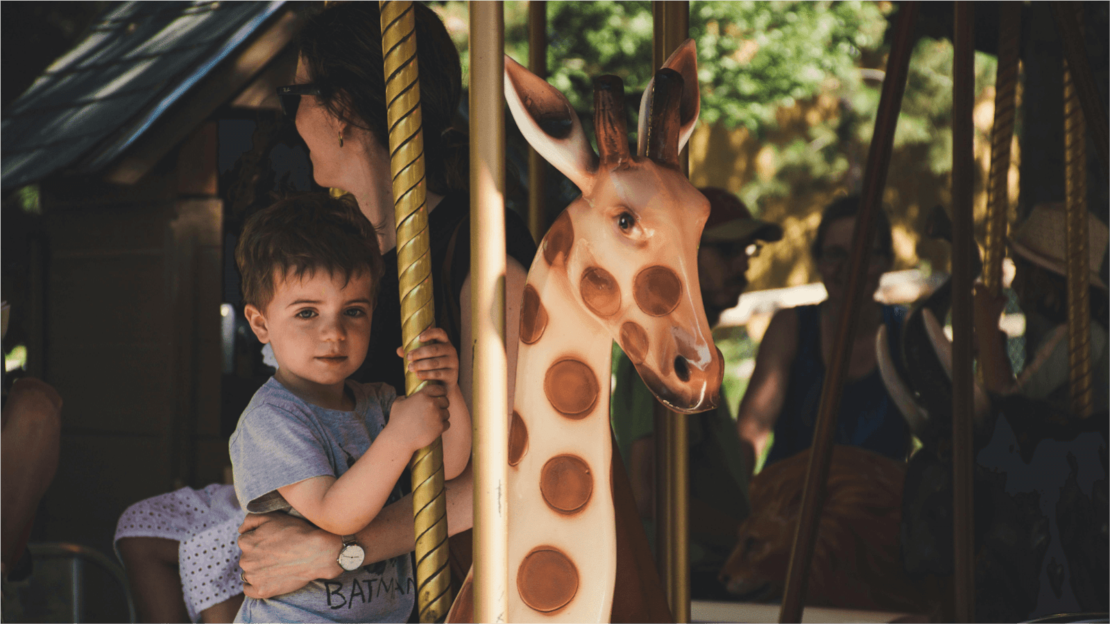 young boy rising a carousel with his mum