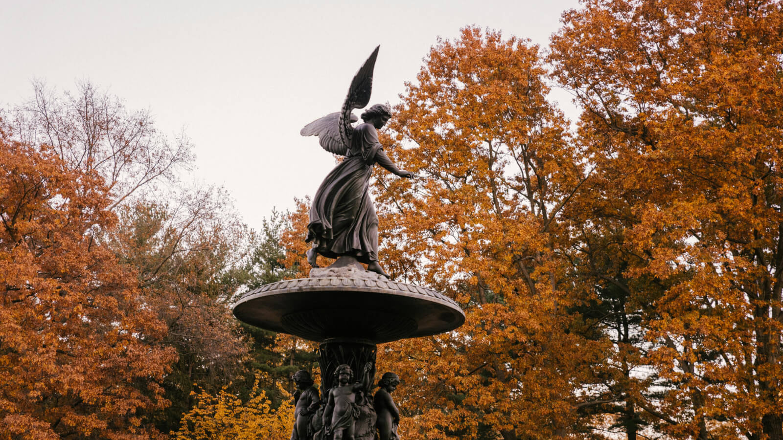 Central Park’s Bethesda Terrace in fall - a photo of the fountain set against burnt orange tree leaves