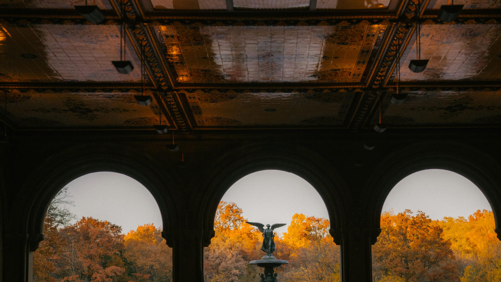 Central Park’s Bethesda Terrace in fall - a photo through the archways showing burnt orange tree leaves
