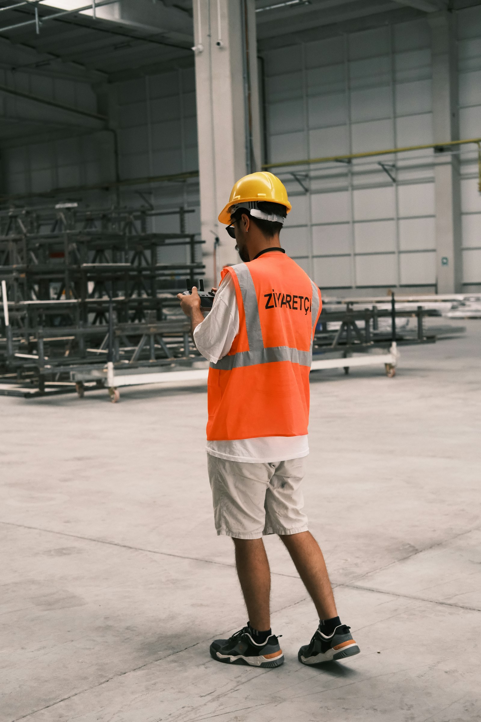 A worker in a safety vest and hard hat in a factory