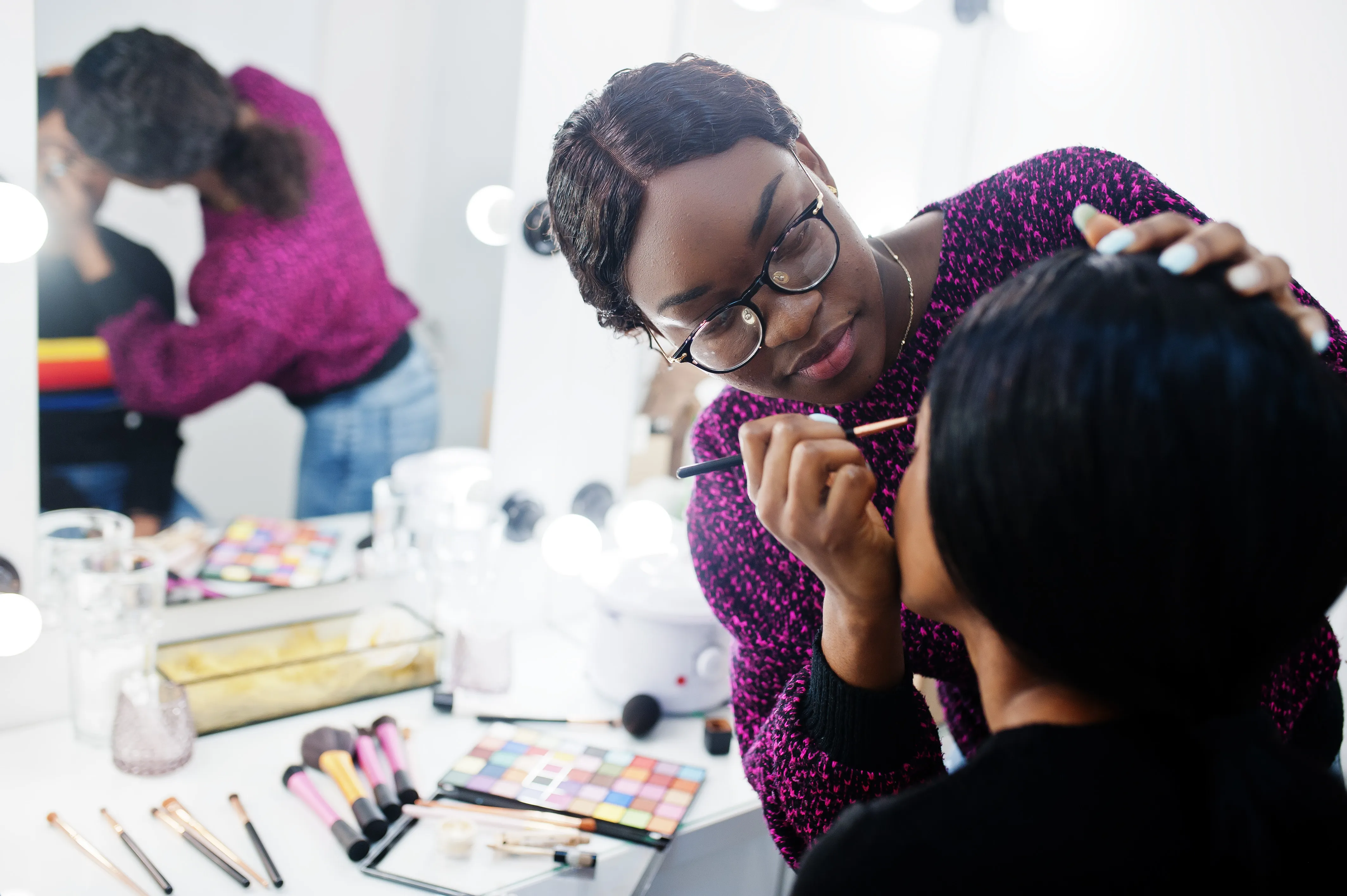 Make Up Artist bedient Kunden vor Spiegel