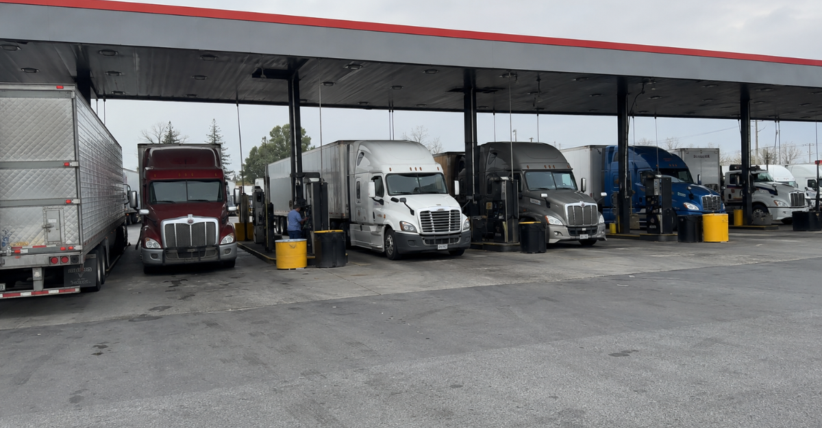 Multiple semi trucks fueling simultaneously at a busy truck stop fuel island
