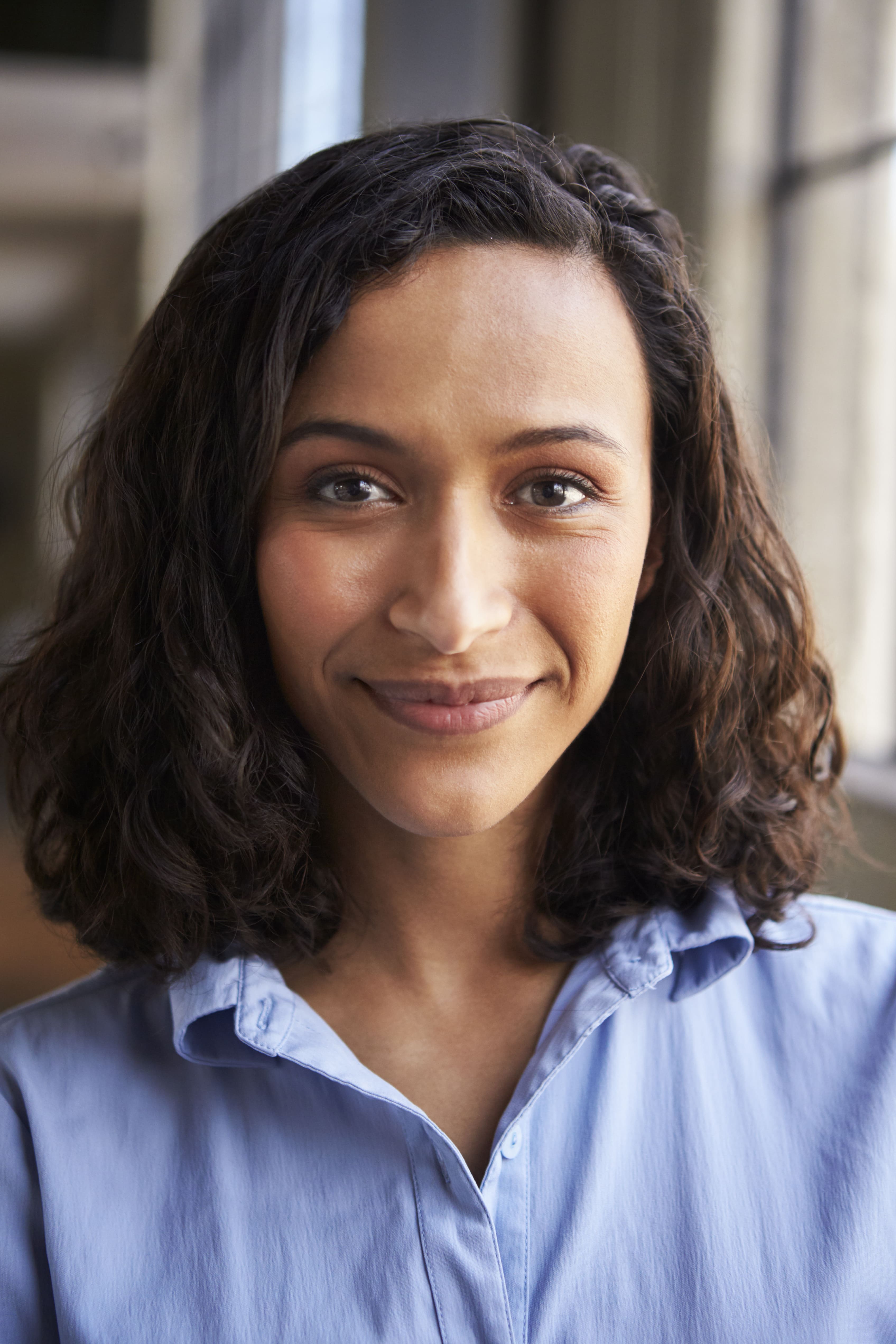 A woman with dark hair and a blue shirt smiling at the camera.