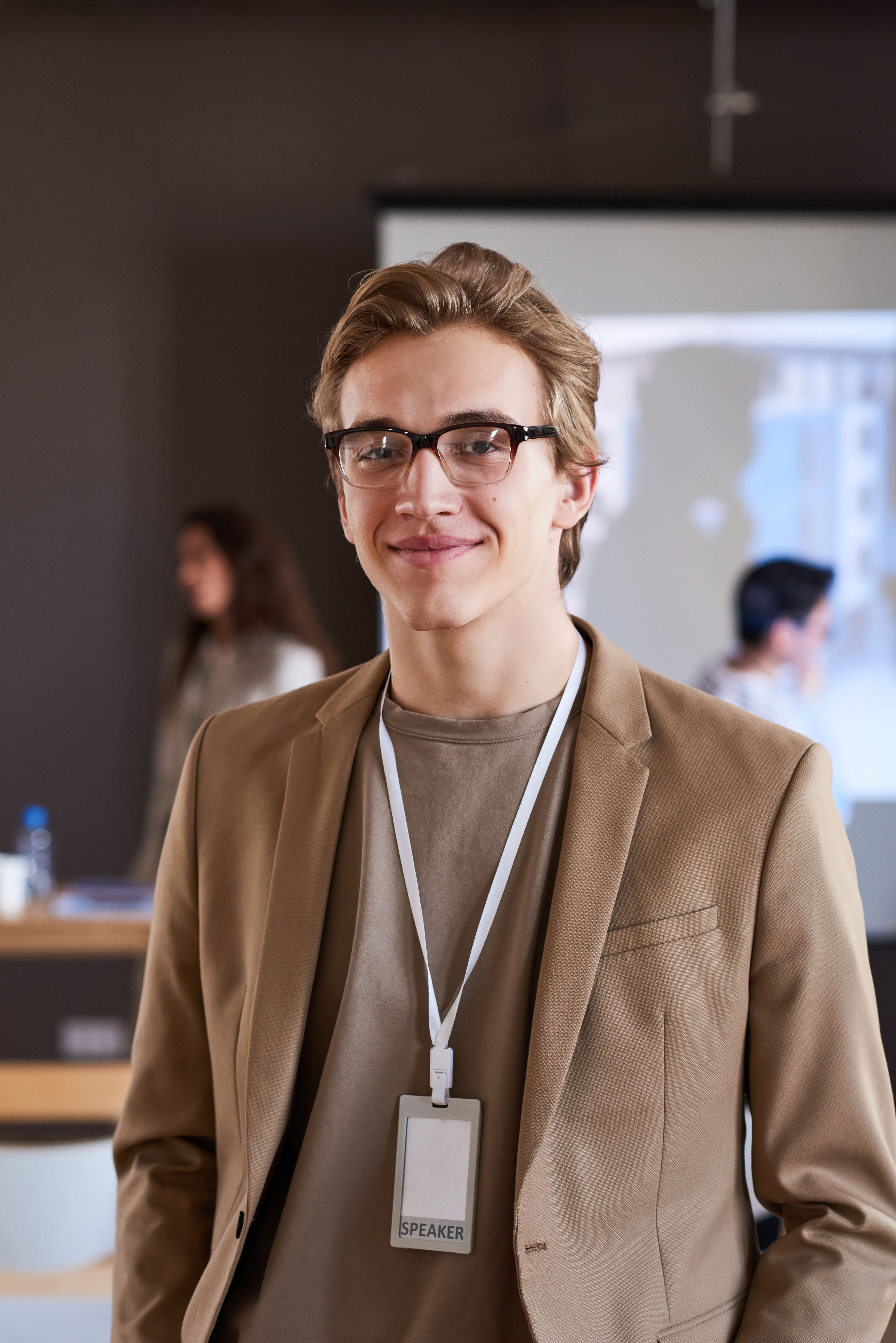 A man wearing glasses and a brown jacket.