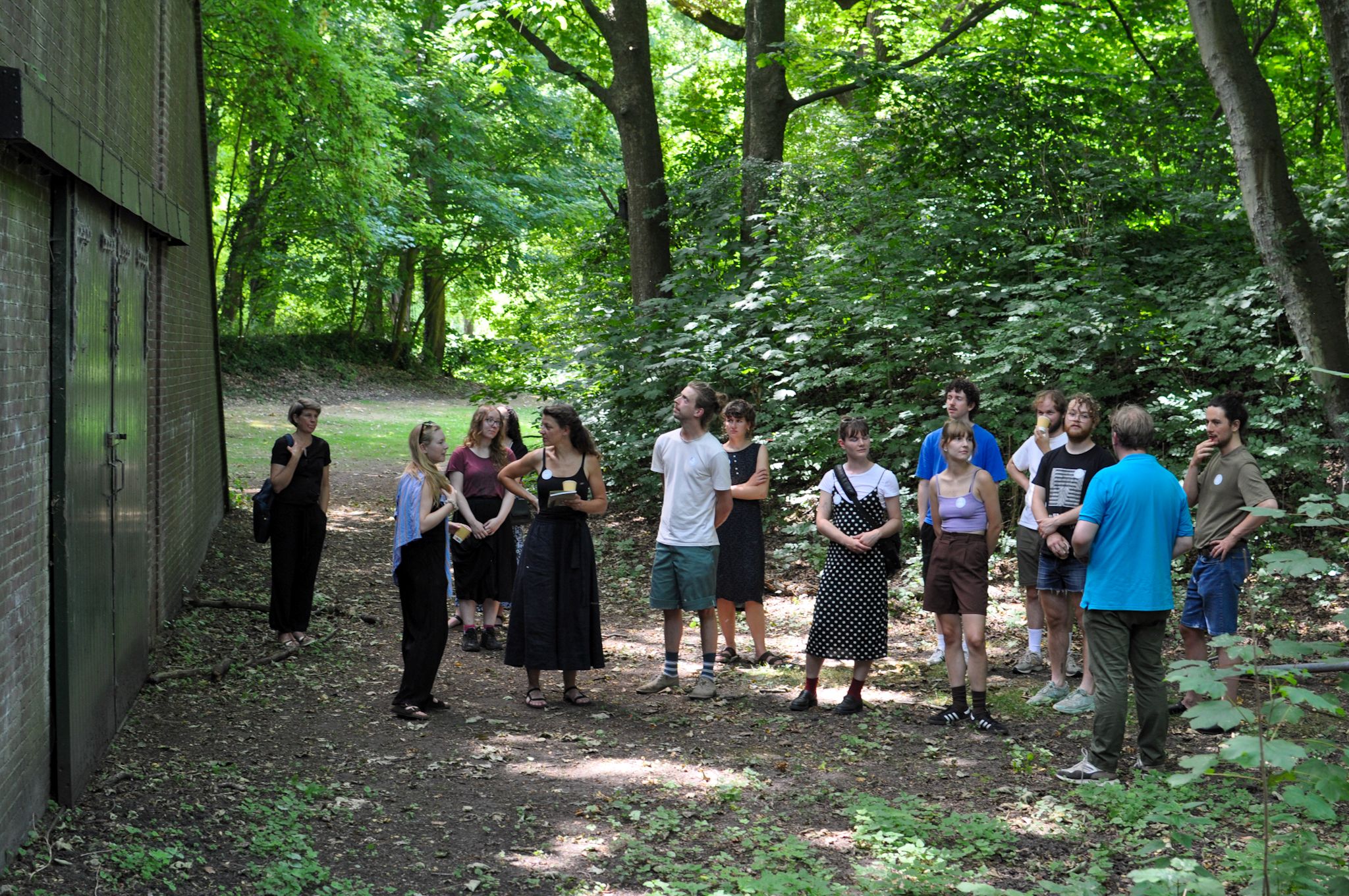 Een groep mensen staat voor een schuur in een bos