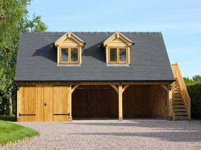 Oak-framed double garage with two upper dormer windows and external wooden staircase.