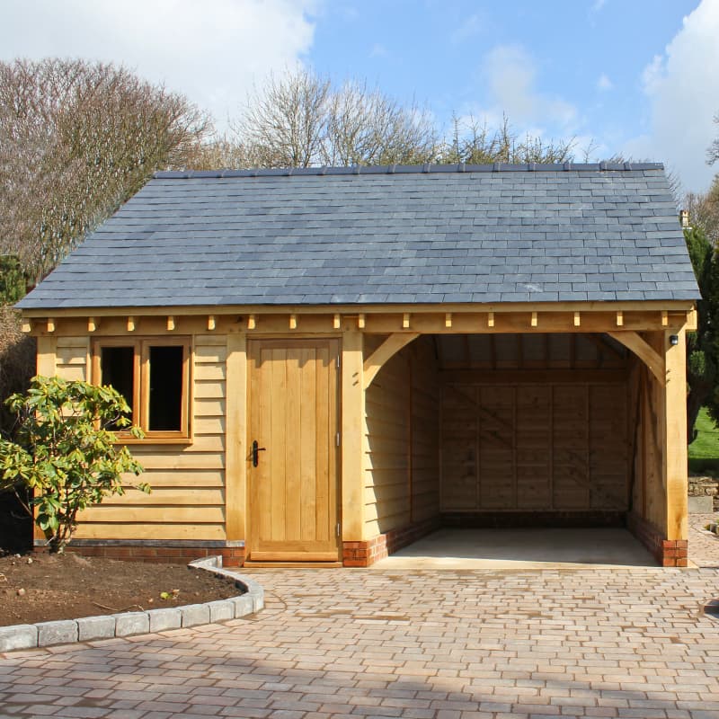 Single-storey oak-framed garage with a slate roof, one bay for carport and one bay for enclosed room.