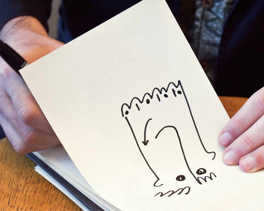 Hand sketching in a sketchbook with a doodle featured from Orgcaos sketches