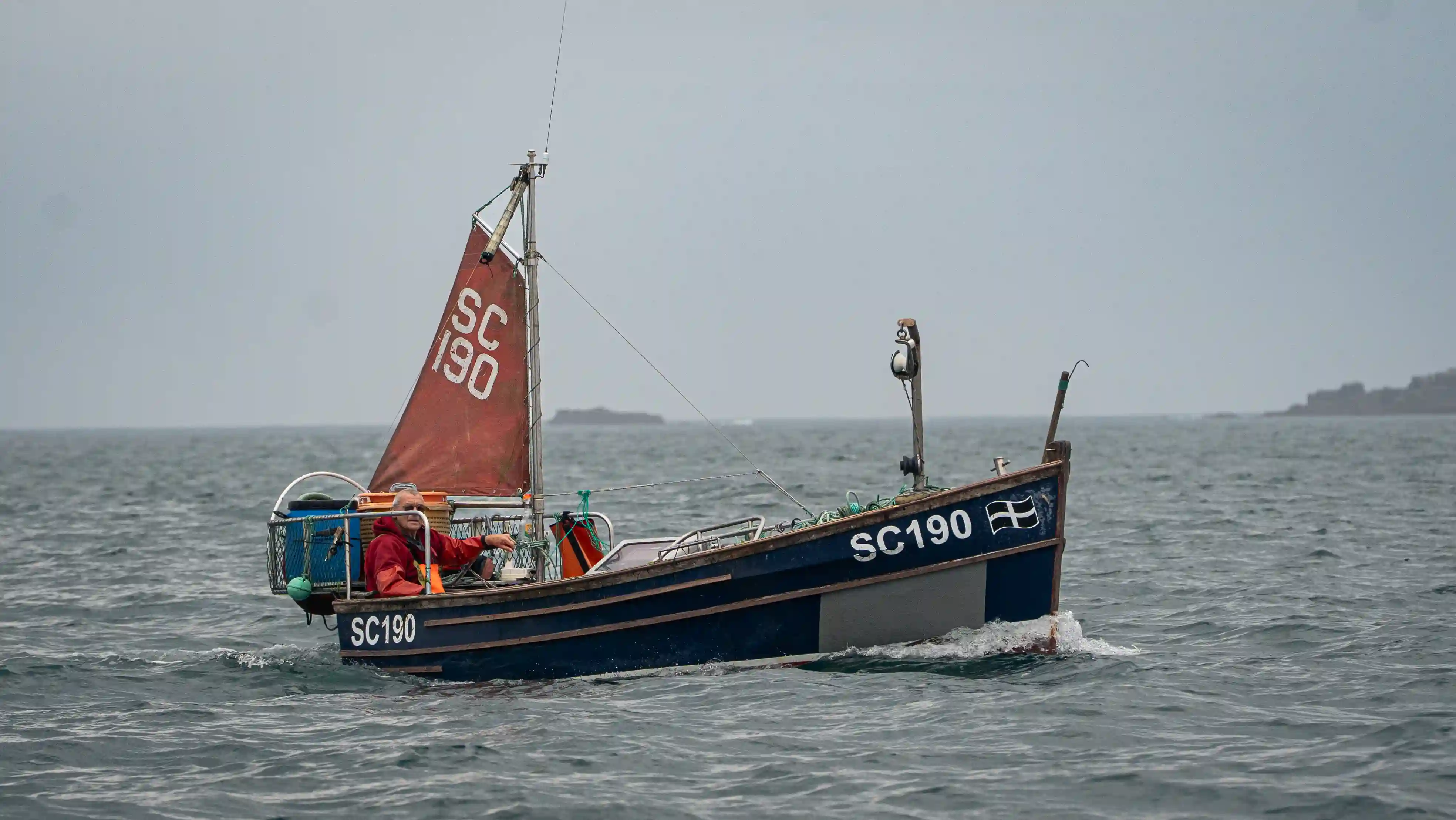 A fishing boat with a red sail 