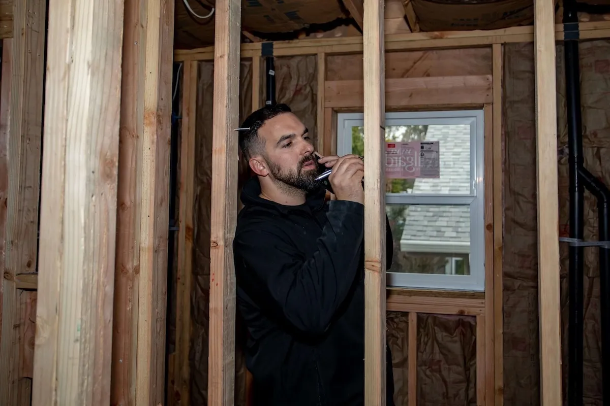 Contractor speaking on phone inside wooden frame structure during home renovation project
