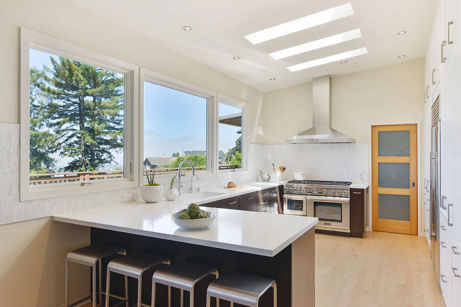 Modern kitchen with vaulted ceiling, wood beams, open shelving, and round dining table